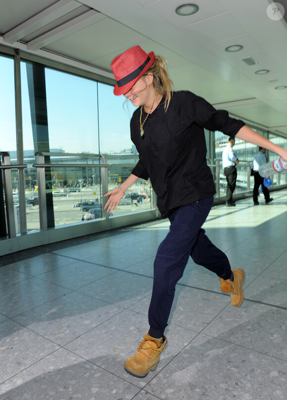 Cara Delevingne, se cachant des photographes, arrive à l'aéroport Heathrow de Londres. Le 2 septembre 2014.