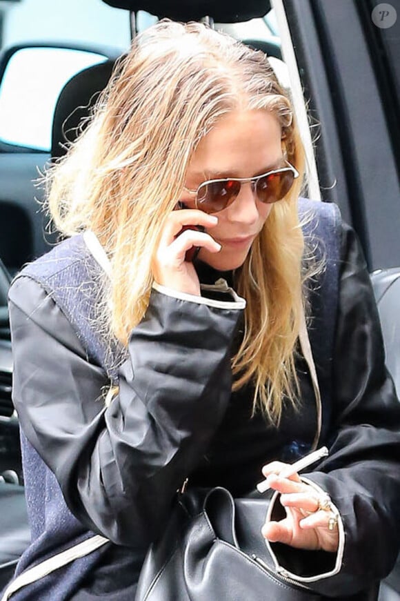 Ashley Olsen, suivie de sa soeur jumelle Mary-Kate qui fume une cigarette, sort d'une voiture à New York, le 8 septembre 2014.