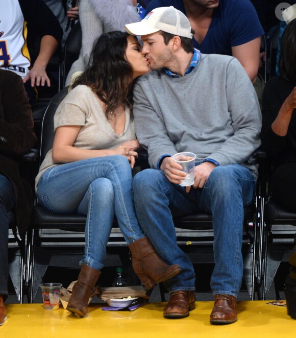 Mila Kunis et son fiancé Ashton Kutcher s'embrassent au match de basket des Lakers face au Thunder d'Oklahoma City, à Los Angeles, le 19 décembre 2014.