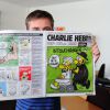 Charb de Charlie Hebdo prend la pose avec le journal à Paris, en 2012.