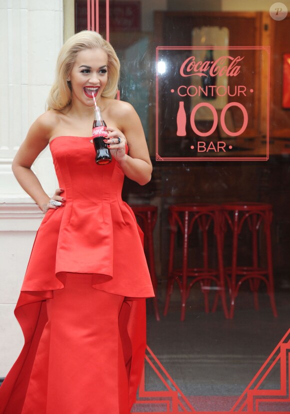 Rita Ora, habillée d'une robe Veni Vici aux couleurs de Coca-Cola, marque les 100 ans de la bouteille en verre de la marque américaine Coca-Cola Contour Centenary Bar. Londres, le 19 mars 2015.