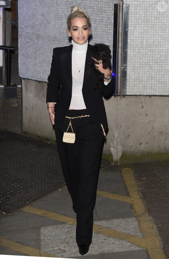 Rita Ora, ultrachic en costume noir, pull à col roulé blanc et ceinture-sacoche matelassée Chanel à la sortie des studios ITV. Londres, le 22 avril 2015.