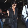 Victoria Beckham, tout de noir vêtue avec un blazer à revers en satin et un chemisier, un jean R13, un sac City Victoria de Victoria Beckham et des bottines Alaïa, décolle de l'aéroport de LAX à Los Angeles. Le 22 avril 2015.