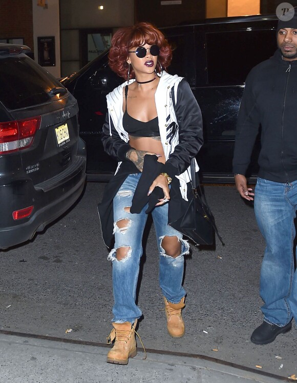 Rihanna à New York, porte des lunettes Le Specs, une veste Joyrich, un soutien-gorge noir, un sac Balenciaga, un jean Acne et des bottines Timberland. Le 2 mai 2015.