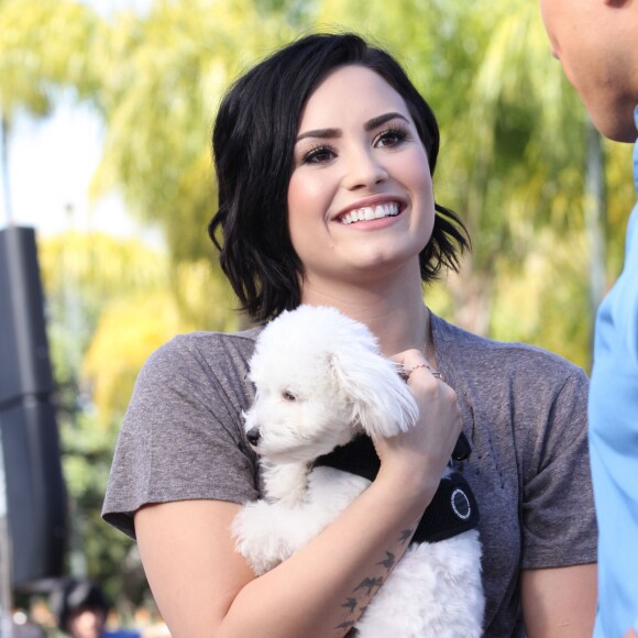 Demi Lovato se rend, accompagnée de son petit caniche blanc, à l'émission "Extra" de Mario Lopez pour une interview à Universal City, le 3 mars 2015