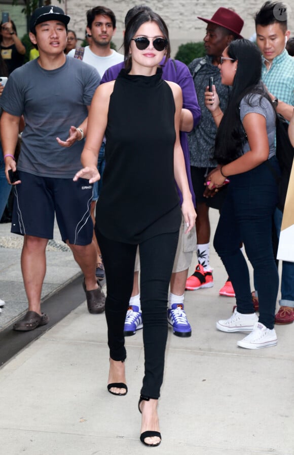 Selena Gomez, toute de noir vêtue à New York, porte des lunettes Christian Dior, un jean 3x1 et des sandales Saint Laurent. Le 20 août 2015.