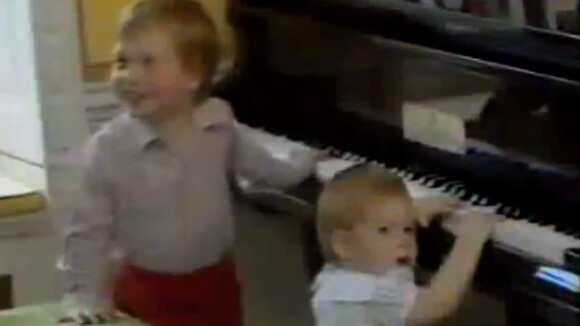 Les princes William et Harry jouant du piano en 1985, chez eux, avec le prince Charles et la princesse Diana.