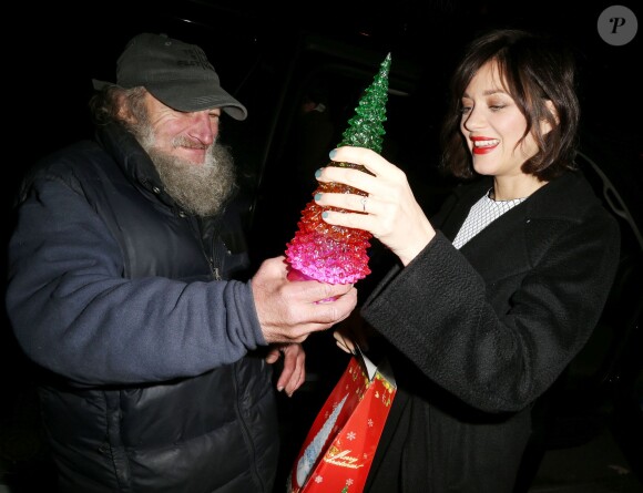 Marion Cotillard reçoit un cadeau du célèbre SDF Radioman à New York le 9 décembre 2015.