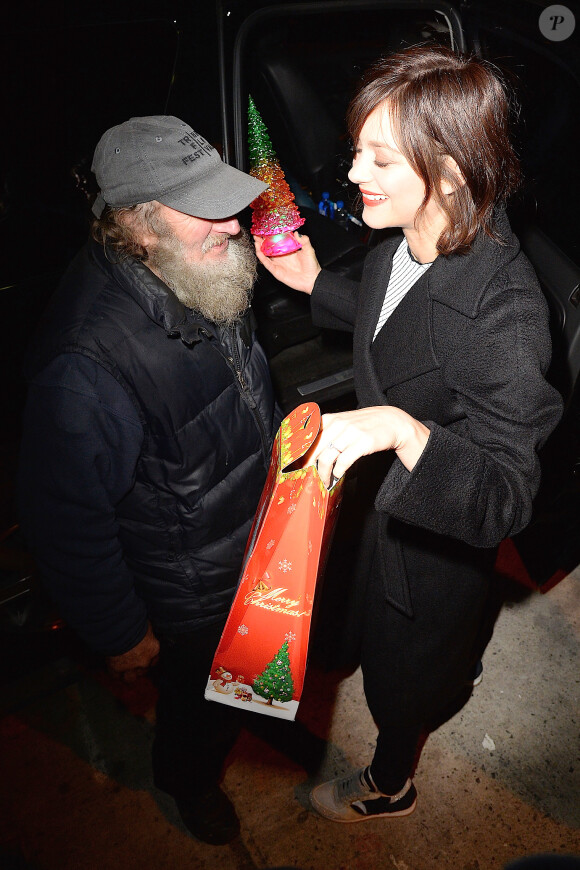 Marion Cotillard reçoit un cadeau du célèbre SDF Radioman à New York le 9 décembre 2015.