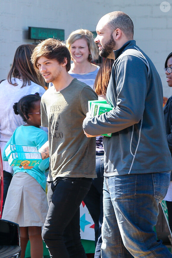 Louis Tomlinson de One Direction participe a une distribution de vivres pour une oeuvre de charité et pose avec ses fans à Los Angeles le 21 février 2016.