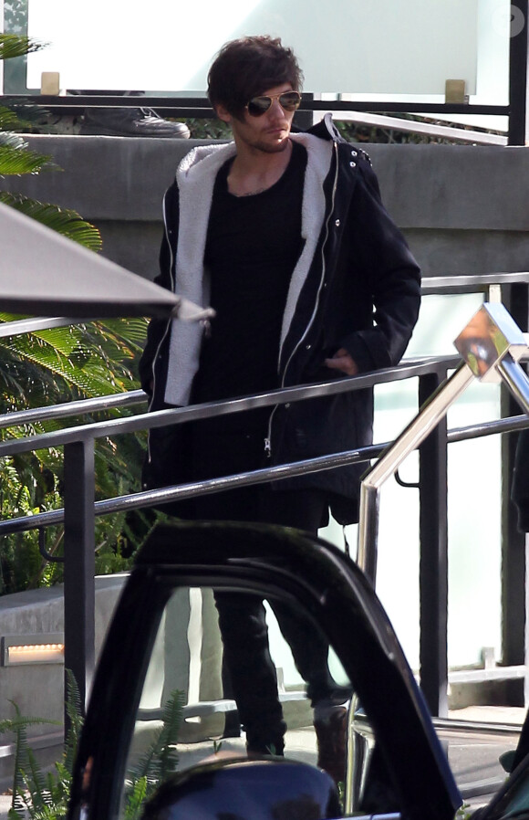 Louis Tomlinson du groupe One Direction quitte son hôtel, son assistant charge une guitare et une XBOX dans la voiture à Beverly Hills le 28 janvier 2016.