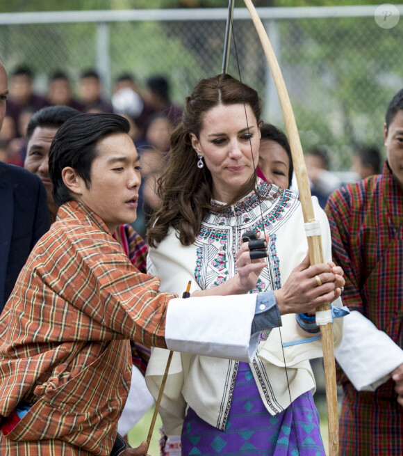 Kate Catherine Middleton, duchesse de Cambridge, s'exerce au tir à l'arc sous l'oeil amusé du prince William, duc de Cambridge, à Thimphou, à l'occasion de leur voyage officiel au Bhoutan. Le 14 avril 2016  14 April 2016. The Duke and Duchess of Cambridge arrive in Bhutan for a two-day visit. One of their engagements took them to the National Stadium where there were some games going on. Both Prince William and Catherine tried their hand at archery and dart throwing.14/04/2016 - Thimphou