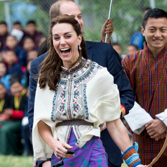 Kate Catherine Middleton, duchesse de Cambridge, s'exerce au tir à l'arc sous l'oeil amusé du prince William, duc de Cambridge, à Thimphou, à l'occasion de leur voyage officiel au Bhoutan. Le 14 avril 2016  14 April 2016. The Duke and Duchess of Cambridge arrive in Bhutan for a two-day visit. One of their engagements took them to the National Stadium where there were some games going on. Both Prince William and Catherine tried their hand at archery and dart throwing.14/04/2016 - Thimphou