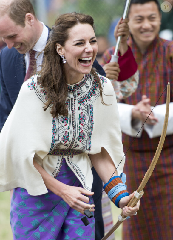 Kate Catherine Middleton, duchesse de Cambridge, s'exerce au tir à l'arc sous l'oeil amusé du prince William, duc de Cambridge, à Thimphou, à l'occasion de leur voyage officiel au Bhoutan. Le 14 avril 2016  14 April 2016. The Duke and Duchess of Cambridge arrive in Bhutan for a two-day visit. One of their engagements took them to the National Stadium where there were some games going on. Both Prince William and Catherine tried their hand at archery and dart throwing.14/04/2016 - Thimphou