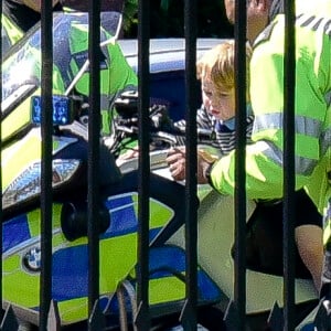 Le prince George de Cambridge est monté sur une moto de la police métropolitaine de Londres le 24 mai 2016 à Kensington Palace, sous les yeux de sa maman Kate Middleton, avec la princesse Charlotte en poussette, après avoir regardé la princesse Anne décoller en hélicoptère pour partir en mission.