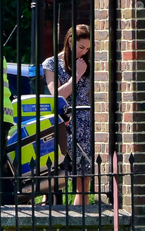 Kate Middleton s'occupe de la princesse Charlotte, en poussette, tandis que le prince George de Cambridge monte sur une moto de la police métropolitaine de Londres le 24 mai 2016 à Kensington Palace.