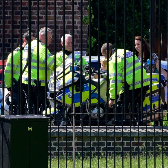 Le prince George de Cambridge est monté sur une moto de la police métropolitaine de Londres le 24 mai 2016 à Kensington Palace, sous les yeux de sa maman Kate Middleton, avec la princesse Charlotte en poussette, après avoir regardé la princesse Anne décoller en hélicoptère pour partir en mission.