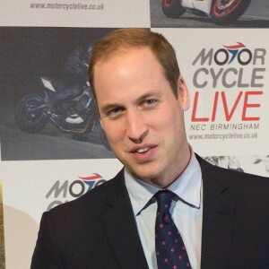 Le prince William, duc de Cambridge, visite le salon de moto Motorcycle Live à Birmingham le 30 novembre 2013 et erçoit en cadeau une petite moto factice pour son fils le prince George.