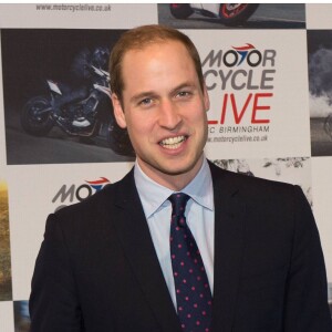 Le prince William, duc de Cambridge, visite le salon de moto Motorcycle Live à Birmingham le 30 novembre 2013 et erçoit en cadeau une petite moto factice pour son fils le prince George.