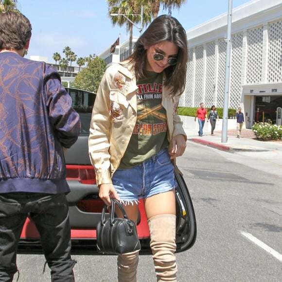 Kendall Jenner arrive au restaurant "Il Pastaio" à Beverly Hills, habillée d'une chemise dorée à broderies, d'un mini-short vintage Levi's (retravaillé par RE/DONE) et de bottes Balmain (collection automne 2016). Des lunettes de soleil Ray-Ban et un sac Givenchy (modèle Lucrezia) complètent sa tenue. Le 13 juin 2016.