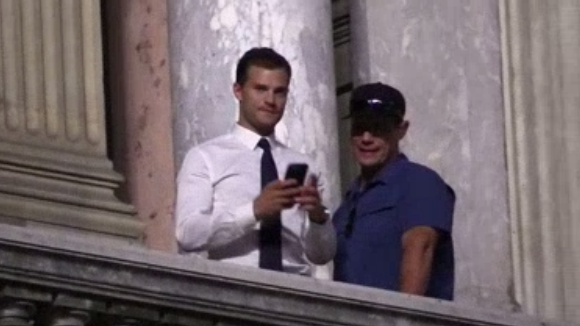 Jamie Dornan et un assistant au balcon de l'Opéra Garnier à Paris le 18 juillet 2016. L'acteur britannique a pris des photos des fans en bas.