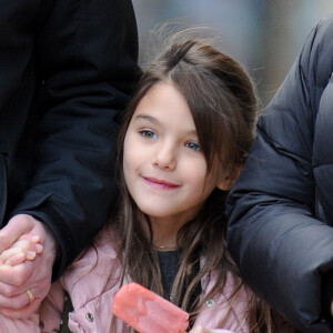 Suri Cruise, souriante, deguste un esquimau alors qu'elle se promene avec sa nounou et son garde du corps a New York, le 11 decembre 2013.