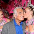 Exclusif - Jean-Paul Belmondo se fait embrasser sur la joue par une danseuse alors qu'il pose dans les coulisses du Moulin-Rouge à Paris le 3 octobre 2016.