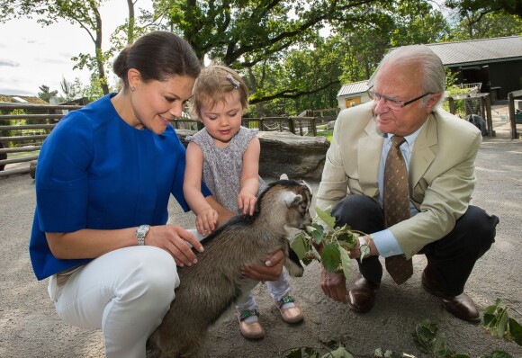 La princesse Estelle de Suède au parc animalier de Skansen avec sa mère la princesse Victoria et son grand-père le roi Carl XVI Gustaf de Suède, en juillet 2014.