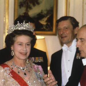 La reine Elizabeth II et François Mitterrand lors d'un dîner d'Etat à l'ambassade de France à Londres en novembre 1984. En arrière-plan, le duc d'Edimbourg, Sir Angus Ogilvy et la princesse Alexandra.