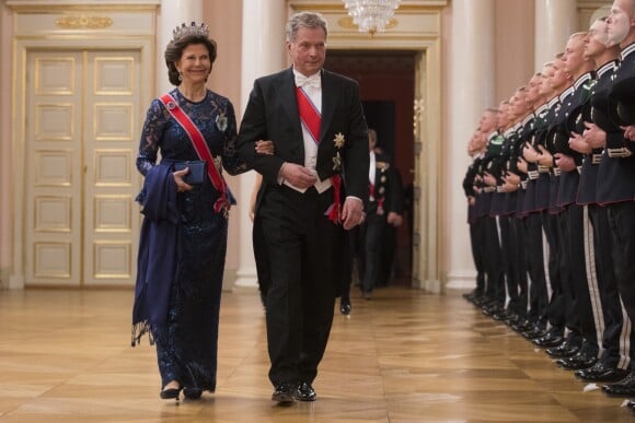 La reine Silvia de Suède au bras du président finlandais Sauli Niinistö arrivant pour le dîner du double 80e anniversaire du roi Harald V de Norvège et de la reine Sonja de Norvège le 9 mai 2017 au palais royal à Oslo.