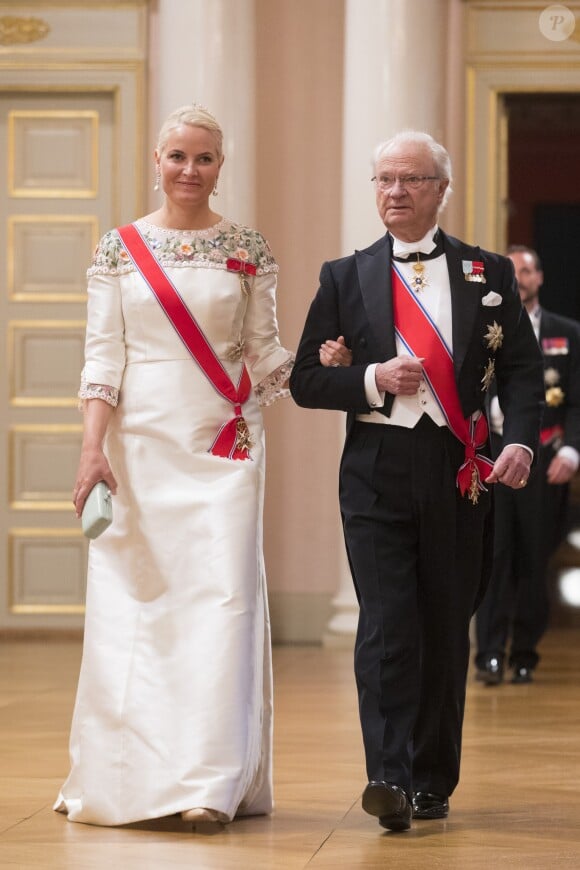 La princesse Mette-Marit de Norvège au bras du roi Carl XVI Gustaf de Suède arrivant pour le dîner du double 80e anniversaire du roi Harald V de Norvège et de la reine Sonja de Norvège le 9 mai 2017 au palais royal à Oslo.