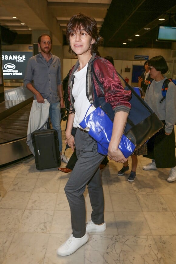 Charlotte Gainsbourg arrive à l'aéroport de Nice, habillée d'un bomber Haider Ackermann (collection masculine printemps-été 2015), tenant un sac sacai et chaussée de baskets Common Projects (modèle Achilles). Le 16 mai 2017.