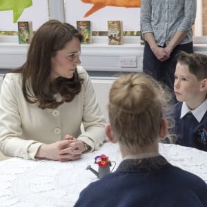 La duchesse Catherine de Cambridge, enceinte de huit mois et vêtue d'un manteau Jojo Maman Bébé, en pleine table ronde avec de jeunes élèves le 6 mars 2018 lors de sa visite à l'école primaire Pegasus à Oxford pour y observer le travail de l'association Family Links UK.