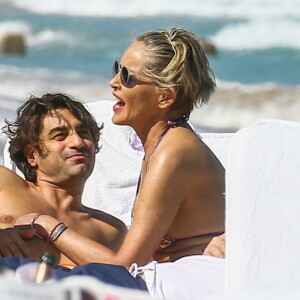 Sharon Stone profite de sa journée avec son nouveau compagnon sur une plage de Miami à la veille des ses 60 ans q'elle fêtera le 10 mars; Miami le 9 mars 2018.  Sharon Stone looked far from single on Thursday as she packed on the PDA with a younger man in Miami and even showed off a diamond ring on her wedding finger. The 59-year-old actress who celebrates her birthday on Saturday, looked incredible in a tiny bikini and striped pants. Miami March 9, 2018.09/03/2018 - Miami