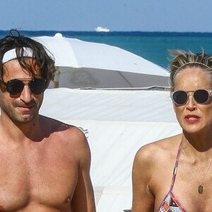 Sharon Stone profite de sa journée avec son nouveau compagnon sur une plage de Miami à la veille des ses 60 ans q'elle fêtera le 10 mars; Miami le 9 mars 2018.  Sharon Stone looked far from single on Thursday as she packed on the PDA with a younger man in Miami and even showed off a diamond ring on her wedding finger. The 59-year-old actress who celebrates her birthday on Saturday, looked incredible in a tiny bikini and striped pants. Miami March 9, 2018.09/03/2018 - Miami