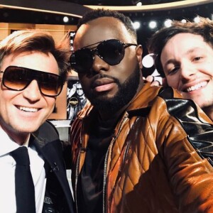 Laurent Delahousse, portant des lunettes de soleil, partage un selfie avec Maître Gims et Vianney sur le plateau de "20h30 le dimanche" sur France 2 le 1er avril 2018.