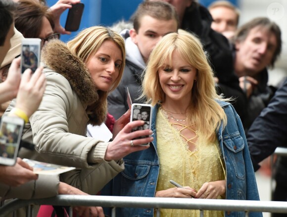 Kylie Minogue, en robe jaune et veste en jean, à la sortie de Quay House à Salford, près de Manchester. Le 23 mars 2018.