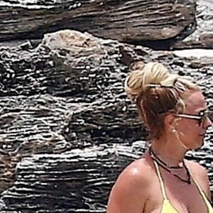 Exclusif - Britney Spears et sa mère Lynn en vacances sur les Îles Turks et Caïques le 22 juin 2019. Sur le film de ses vacances, Britney n'hésite pas à faire ses cascades elle-même. Elle escalade un rocher à mains nues et en tong sous l'oeil rassurant de sa mère. Aucune autre protection que son petit bikini jaune. Après cette montée d'adrénaline, la chanteuse fait trempette dans les eaux bleues de la crique et le duo mère - fille rejoint les transats.