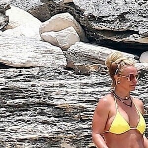 Exclusif - Britney Spears et sa mère Lynn en vacances sur les Îles Turks et Caïques le 22 juin 2019. Sur le film de ses vacances, Britney n'hésite pas à faire ses cascades elle-même. Elle escalade un rocher à mains nues et en tong sous l'oeil rassurant de sa mère. Aucune autre protection que son petit bikini jaune. Après cette montée d'adrénaline, la chanteuse fait trempette dans les eaux bleues de la crique et le duo mère - fille rejoint les transats.