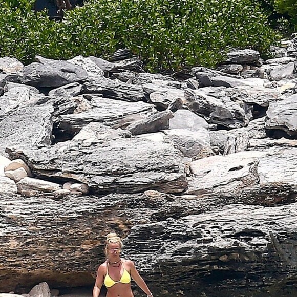 Exclusif - Britney Spears et sa mère Lynn en vacances sur les Îles Turks et Caïques le 22 juin 2019. Sur le film de ses vacances, Britney n'hésite pas à faire ses cascades elle-même. Elle escalade un rocher à mains nues et en tong sous l'oeil rassurant de sa mère. Aucune autre protection que son petit bikini jaune. Après cette montée d'adrénaline, la chanteuse fait trempette dans les eaux bleues de la crique et le duo mère - fille rejoint les transats.