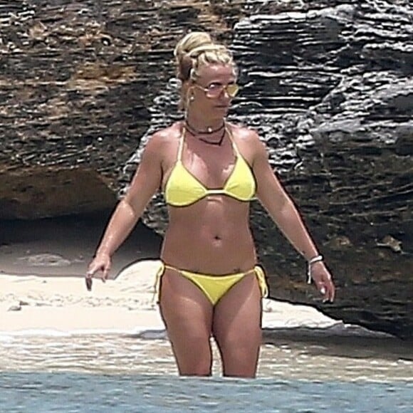 Exclusif - Britney Spears et sa mère Lynn en vacances sur les Îles Turks et Caïques le 22 juin 2019. Sur le film de ses vacances, Britney n'hésite pas à faire ses cascades elle-même. Elle escalade un rocher à mains nues et en tong sous l'oeil rassurant de sa mère. Aucune autre protection que son petit bikini jaune. Après cette montée d'adrénaline, la chanteuse fait trempette dans les eaux bleues de la crique et le duo mère - fille rejoint les transats.
