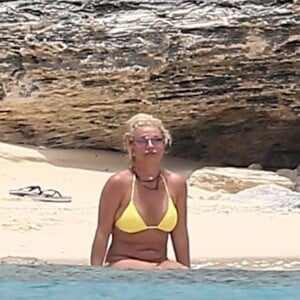 Exclusif - Britney Spears et sa mère Lynn en vacances sur les Îles Turks et Caïques le 22 juin 2019. Sur le film de ses vacances, Britney n'hésite pas à faire ses cascades elle-même. Elle escalade un rocher à mains nues et en tong sous l'oeil rassurant de sa mère. Aucune autre protection que son petit bikini jaune. Après cette montée d'adrénaline, la chanteuse fait trempette dans les eaux bleues de la crique et le duo mère - fille rejoint les transats.