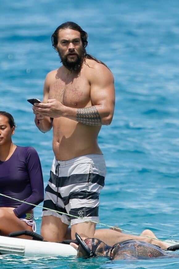 Exclusif -Jason Momoa,en maillot de bain et très musclé, s'amuse avec des amis en vacances à Honolulu, Hawaï le 8 juin 2018. Le héros du film "Aquaman" s'est amusé à jeter son portable dans l'eau puis a plongé pour aller le récupérer. Espérons qu'il aura un bon sachet de riz après pour son portable.