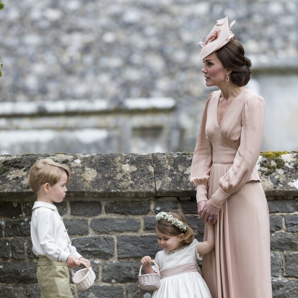 Kate Middleton, en robe Alexander McQueen, avec son fils le prince George et sa fille la princesse Charlotte, au mariage de sa soeur Pippa Middleton et James Matthew, en l'église St Mark Englefield, Berkshire, le 20 mai 2017.