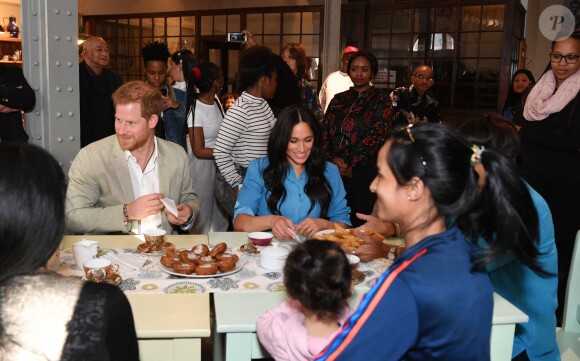 Le prince Harry, duc de Sussex, et Meghan Markle, duchesse de Sussex, en visite dans un e cuisine communautaire dans le District 6 au Cap dans le cadre de leur visite officielle en Afrique du Sud, le 23 septembre 2019.