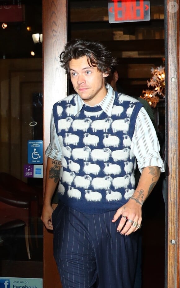 Harry Styles porte un pull avec des moutons tricotés à la sortie d'un immeuble à New York, le 12 novembre 2019.