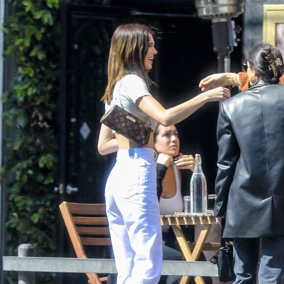 Kendall Jenner est allée déjeuner avec des amis au restaurant Croft Alley dans le quartier de West Hollywood à Los Angeles. Elle porte un jean taille haute blanc, un sac Louis Vuitton et un crop top sans soutien gorge. Le 11 mars 2020.