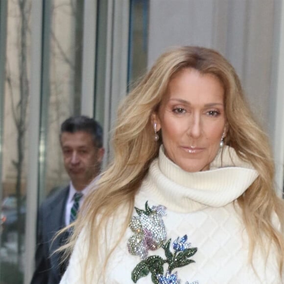 Celine Dion rayonnante et très souriante dans un ensemble pull écru et jupe bouffante fleurie salue ses fans à la sortie de son hôtel à New York, le 8 mars 2020