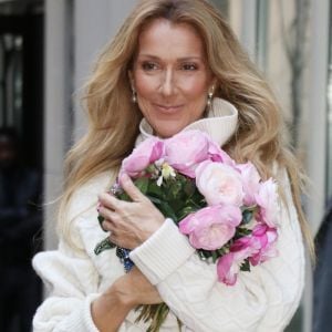 Celine Dion rayonnante et très souriante dans un ensemble pull écru et jupe bouffante fleurie salue ses fans à la sortie de son hôtel à New York, le 8 mars 2020