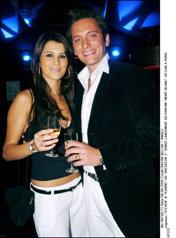 Karine Ferri en jean blanc, top à bretelles noir et boucles d'oreilles créoles, prend la pose au cpoté de Steven du "Bachelor 2" lors de la soirée de lancement du parfum "Mont Blanc" en 2004.